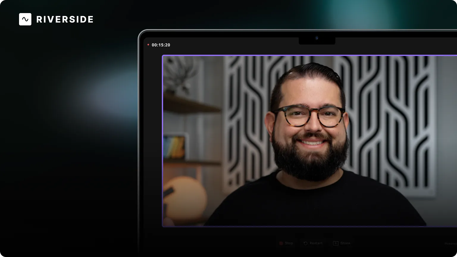 A smiling man with glasses and beard on a video call screen, with a patterned background and a globe on a shelf behind him.